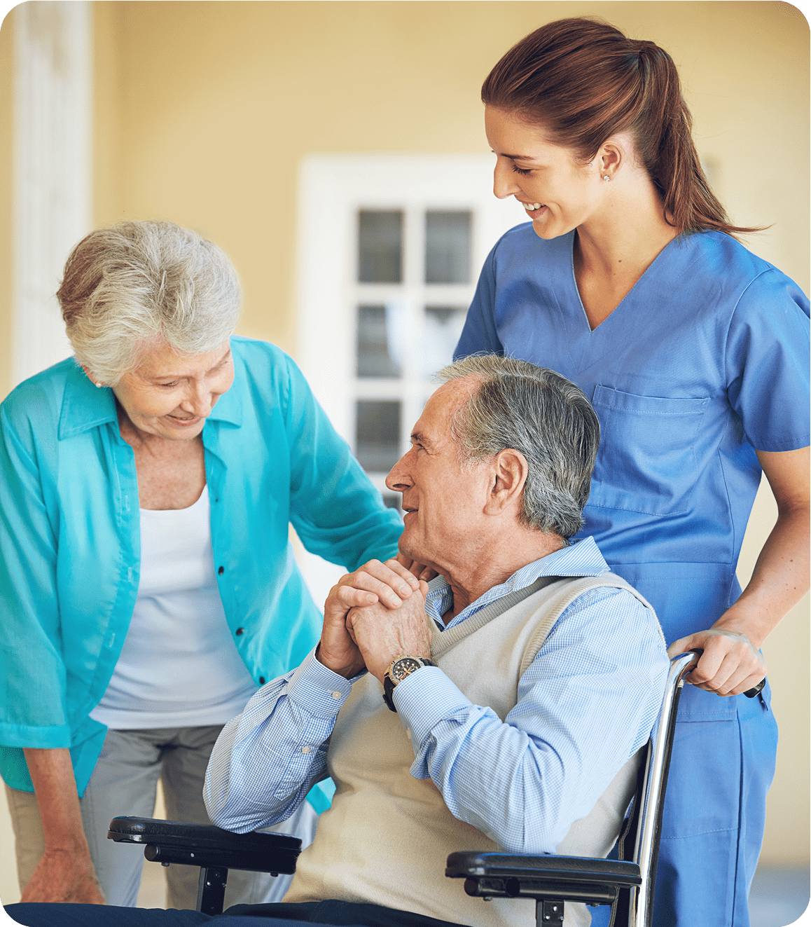 Elderly man in wheelchair with caregivers smiling.