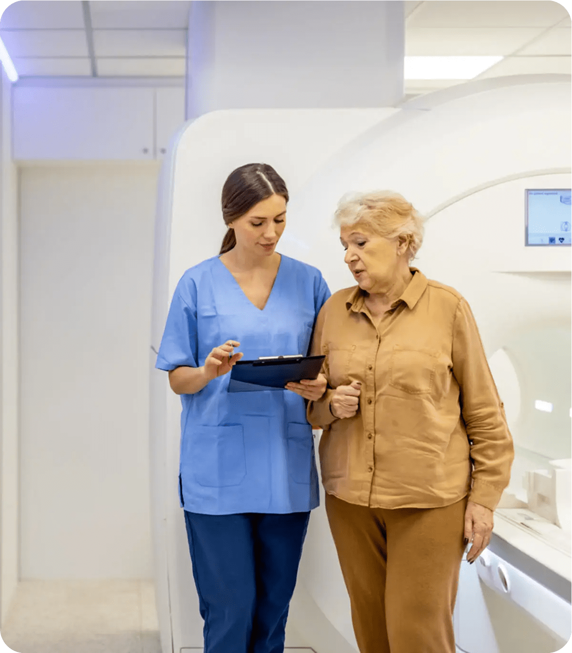 Nurse assisting elderly woman near MRI machine.